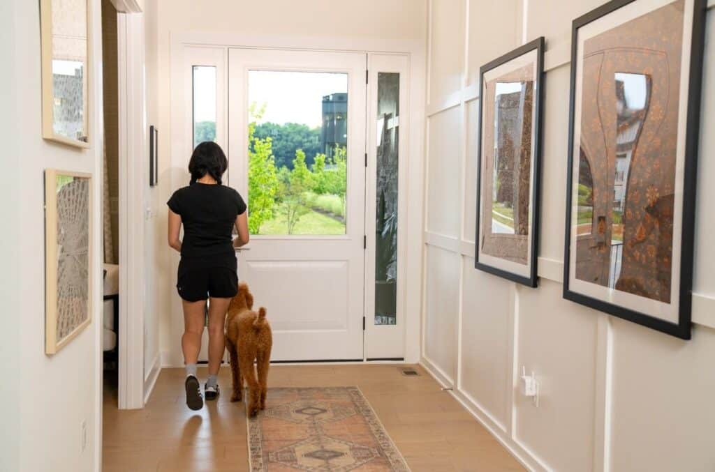 A woman standing with her back to the door, with a dog beside her, emphasizing a secure and welcoming home environment.