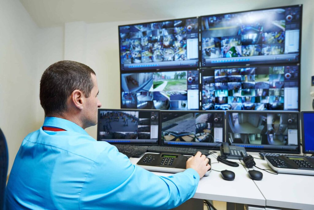 Person Monitoring CCTV Footage on Multiple Screens